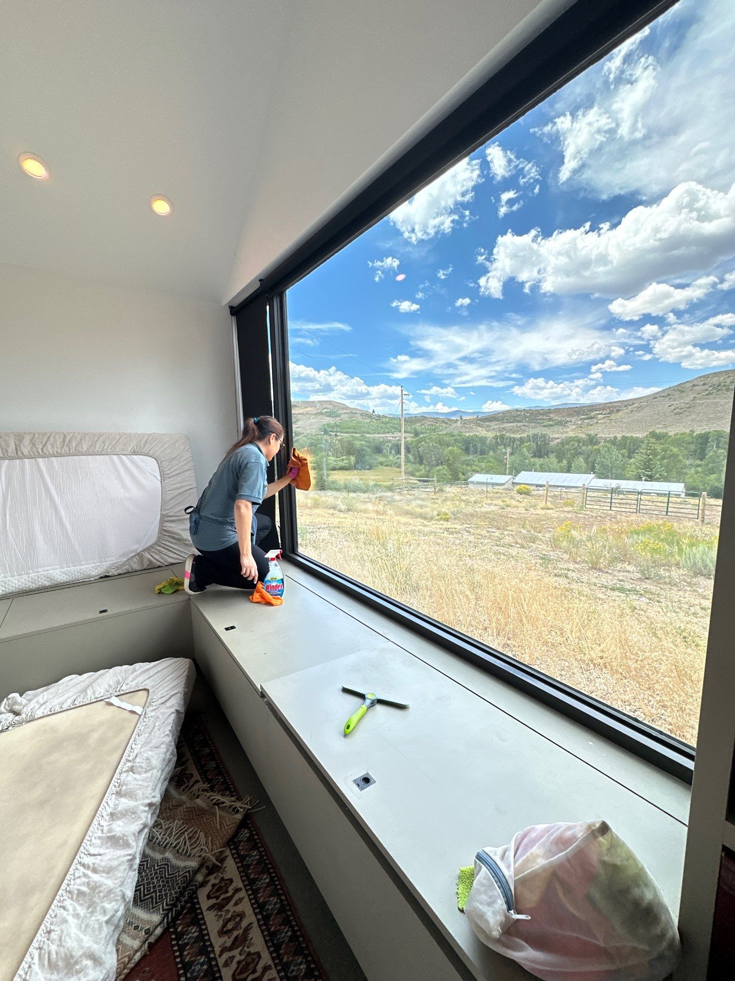 Wheatley Creek Services team member cleaning a large picture window with a Grand County Colorado mountain view